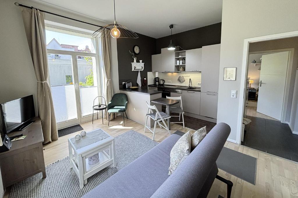 a living room with a blue couch and a kitchen at Ferienwohnung Truding in Stralsund