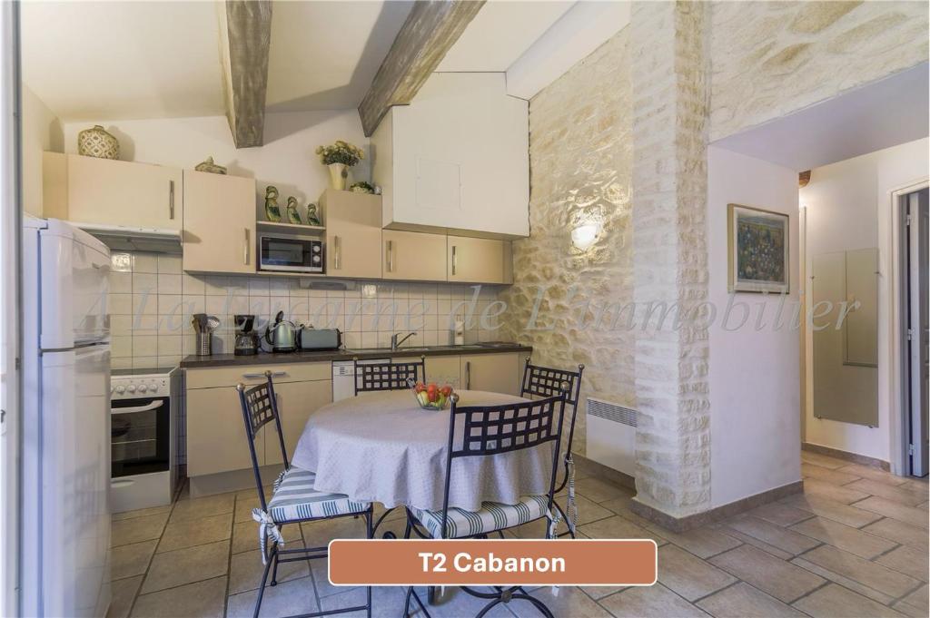 a kitchen with a table and chairs in a room at L'Arc en Ciel in Gréoux-les-Bains