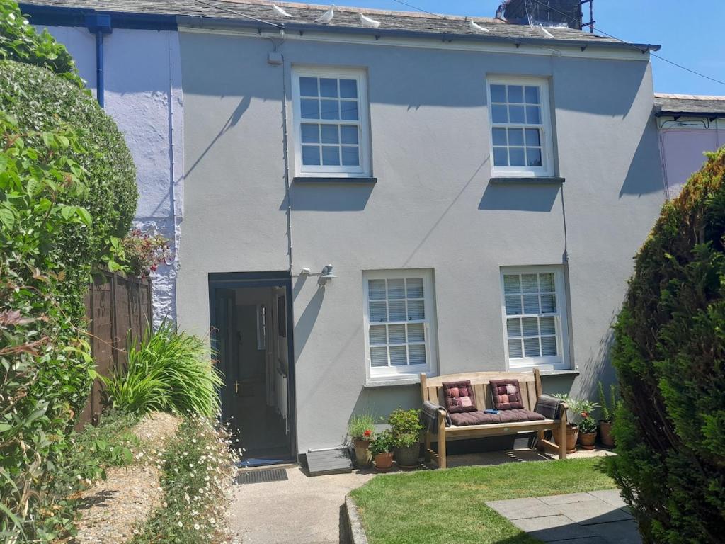 a white house with a bench in front of it at The Captain's House Charlestown St Austell in Charlestown