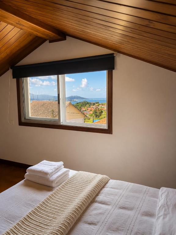 a bedroom with a window with towels on a bed at Casa do Carballo in Nigrán