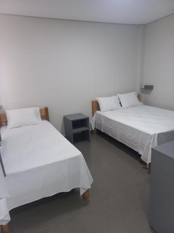 two beds in a room with white walls at Hotel Parada KM364 in Santo Antonio do Rio Abaixo