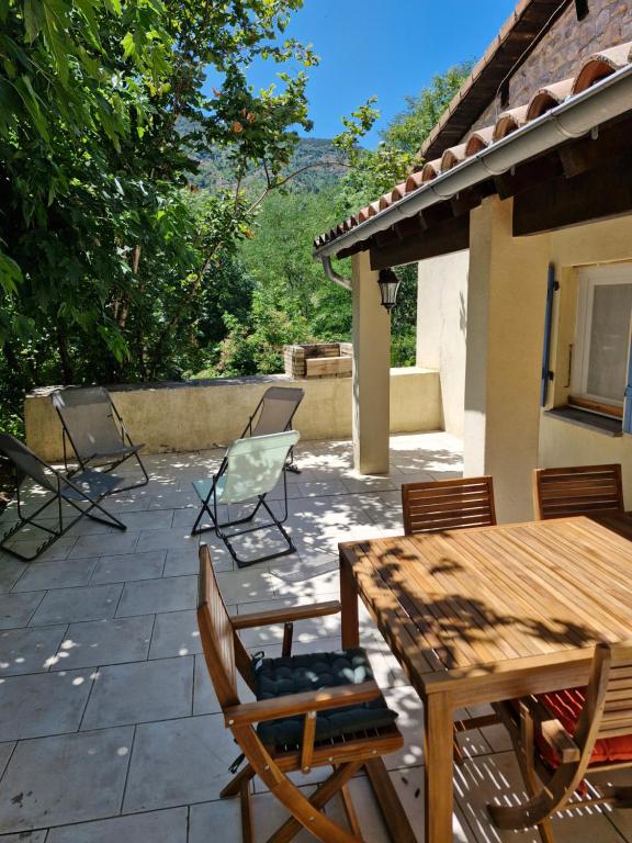 a patio with a wooden table and chairs at Maison en pierre Ardèche du sud in Valgorge