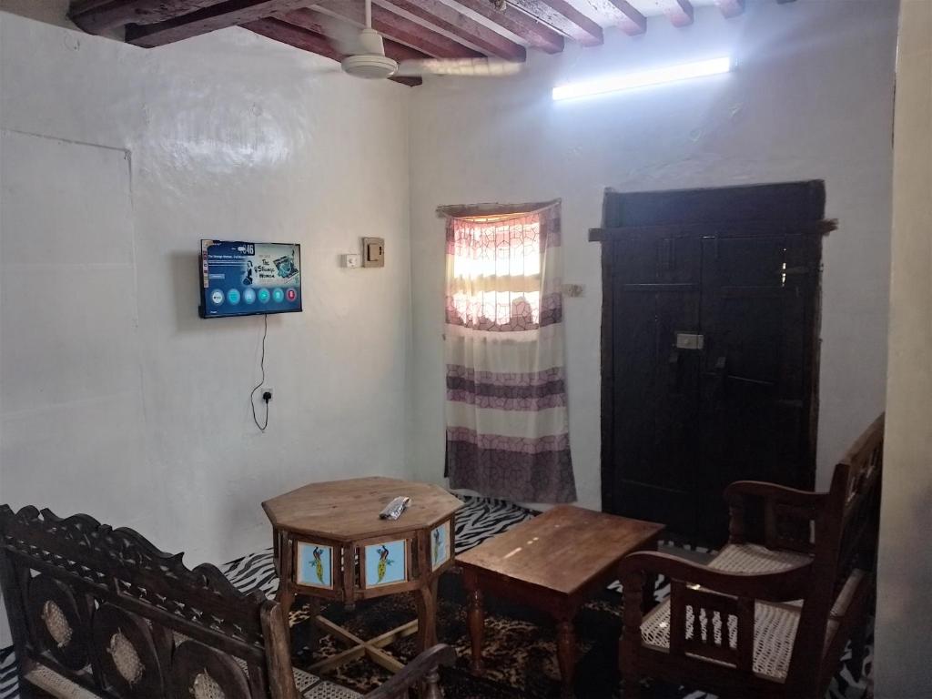 a room with a table and chairs and a black door at Beiytul Noor Apartment in Lamu