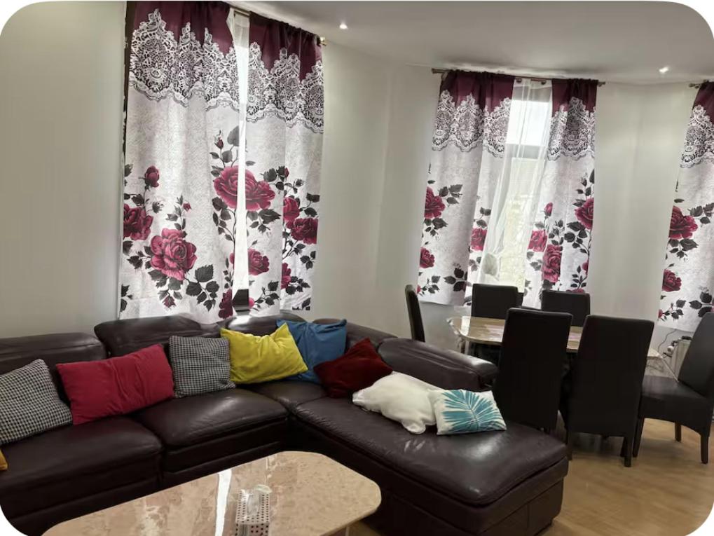 a living room with a black leather couch with colorful pillows at Grace Family Home 2 in Brussels