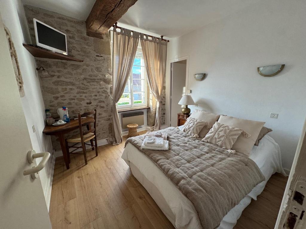 a bedroom with a bed and a table and a window at Ancien hôtel du Thaurion in Saint-Hilaire-le-Château