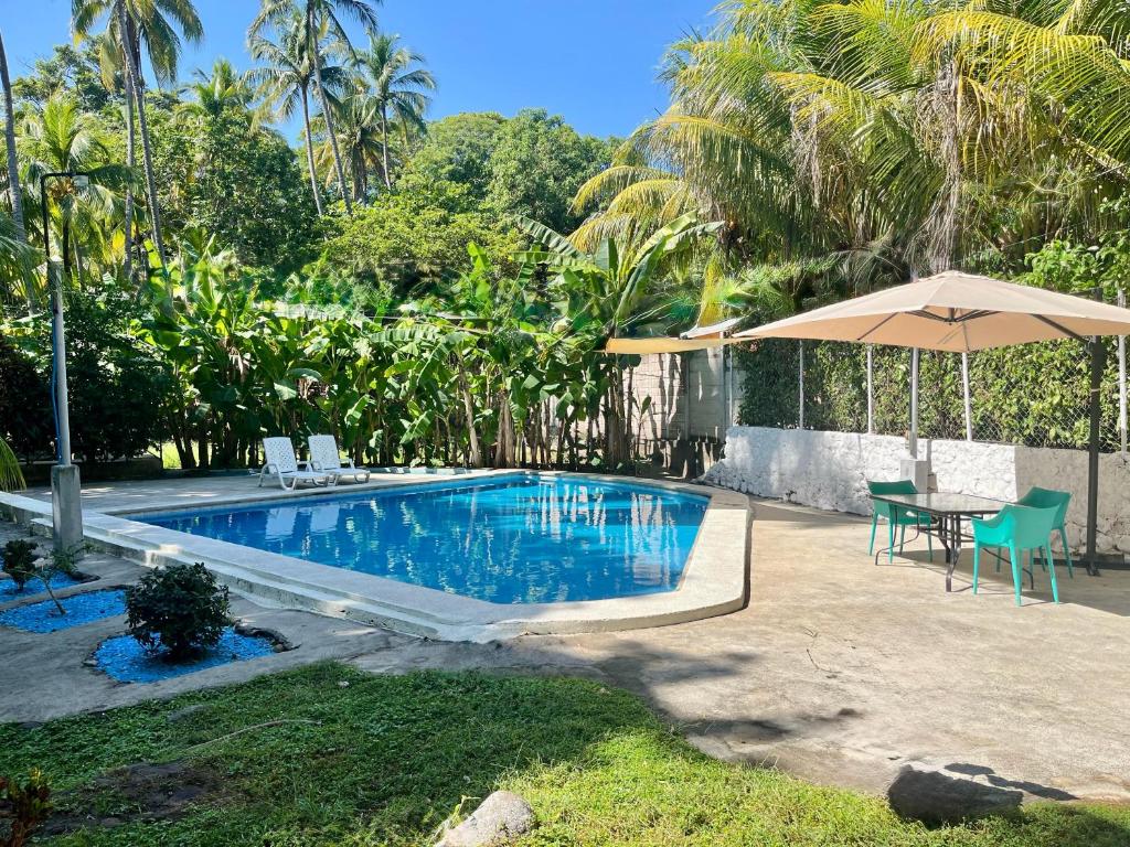 a swimming pool with a table and an umbrella at Beach House EL Cocalito in La Libertad