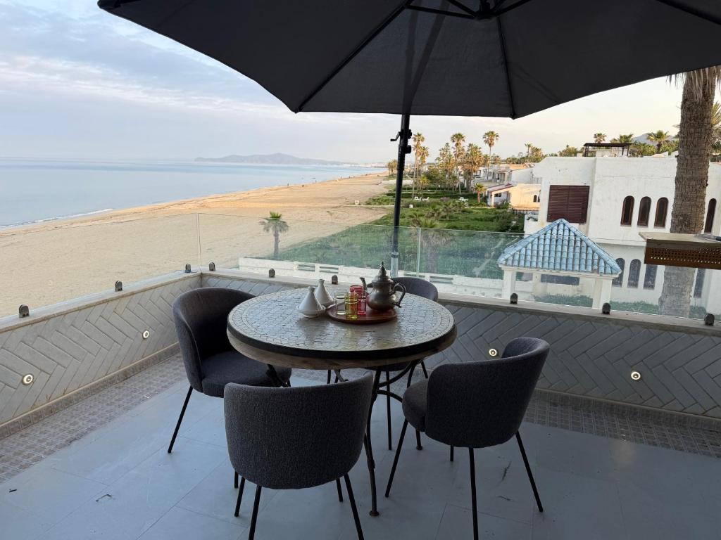 a table and chairs on a balcony with a view of the beach at Alamine plage in Fnidek
