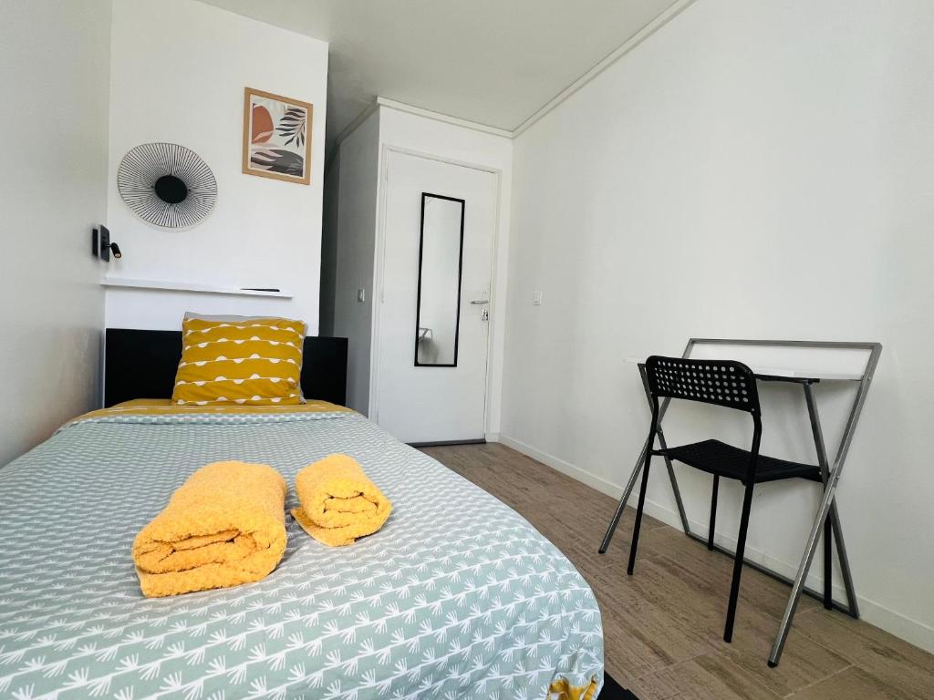 a bedroom with a bed with yellow pillows and a chair at Chambre salle d'eau privée in Brest