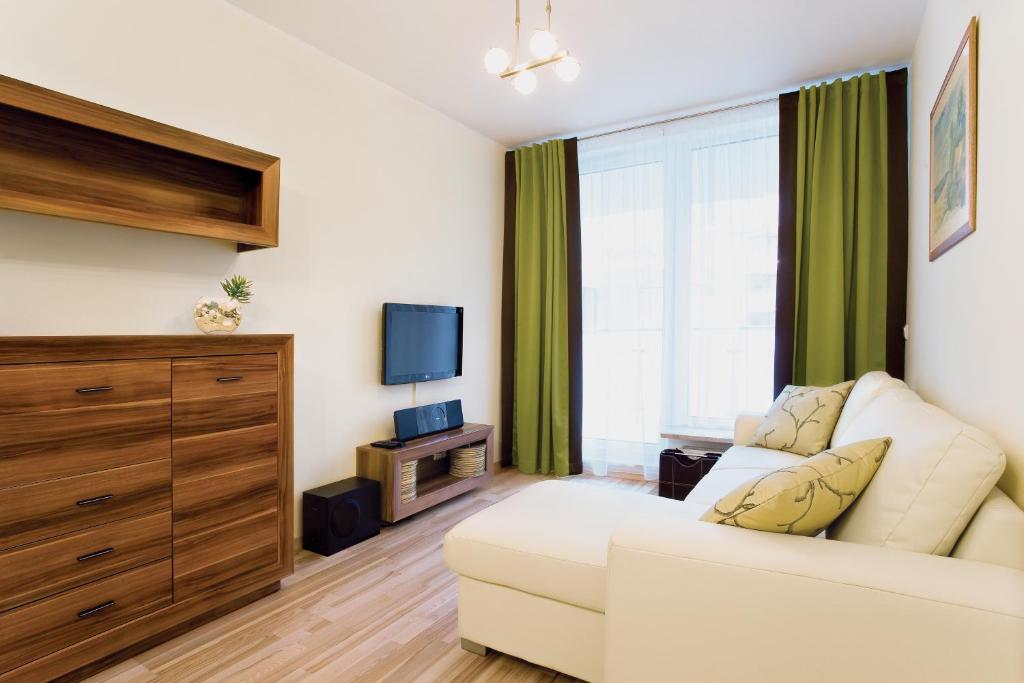a living room with a white couch and a tv at Apartament Aquamarina Międzyzdroje in Międzyzdroje