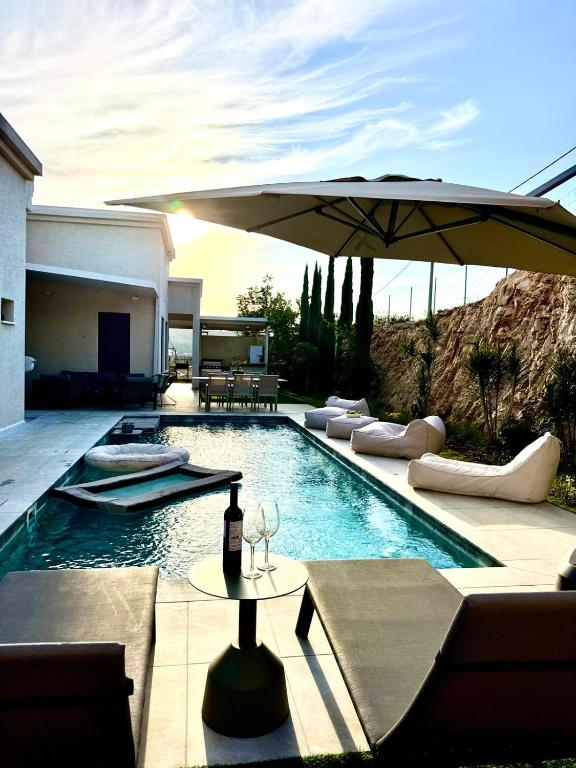 a swimming pool with a table and an umbrella at Villa Casa Blanca in Kefar H̱ananya