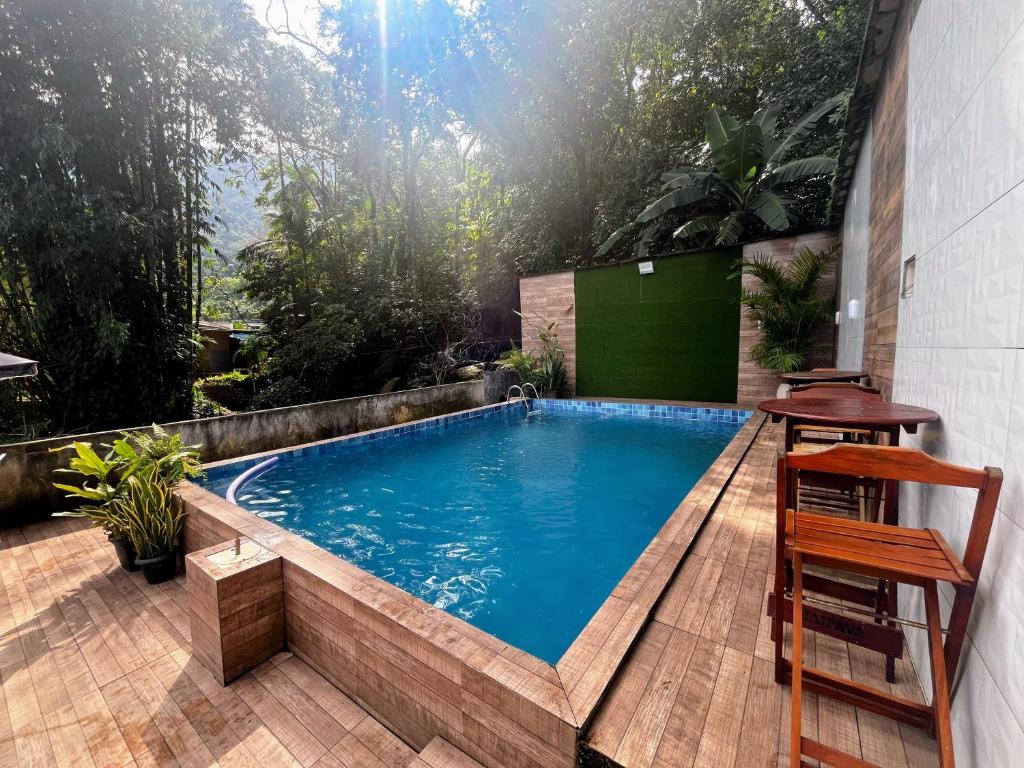 a swimming pool with a table and two stools at My House Muriqui in Mangaratiba