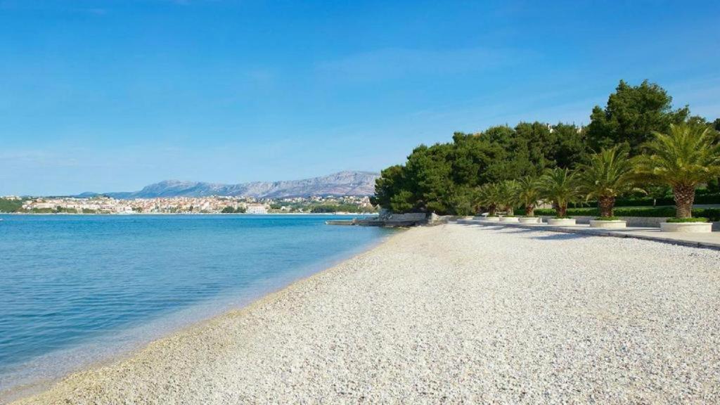 a beach with trees and the water on a sunny day at Pine Residence at Lav Meridien Resort in Podstrana