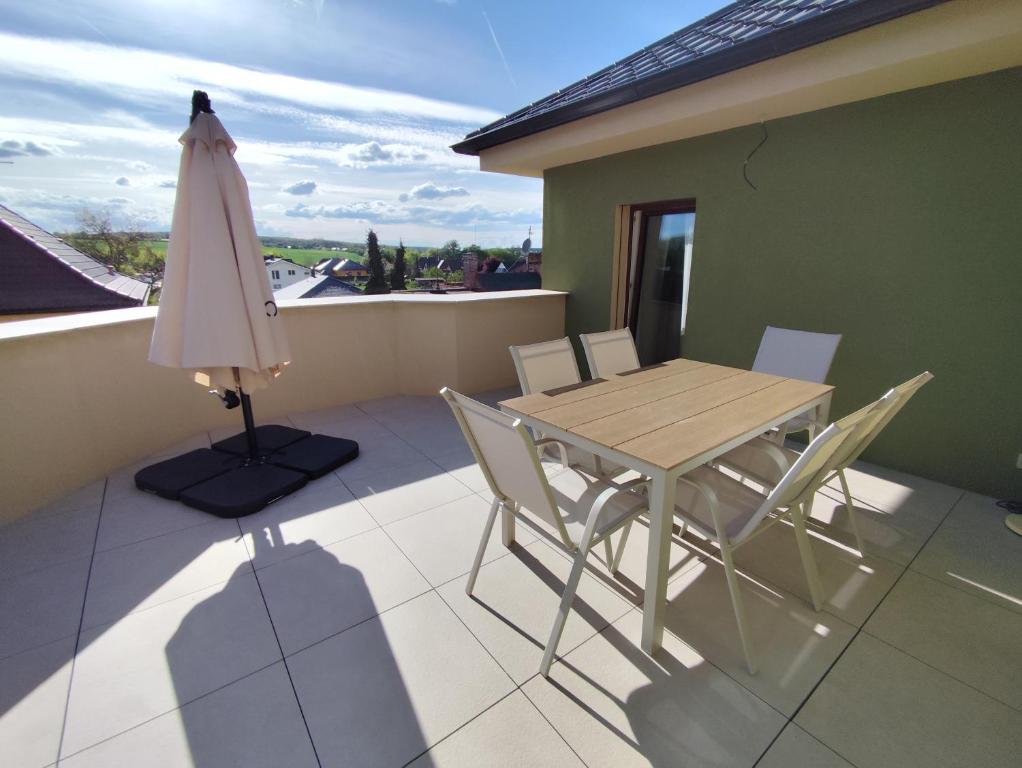a table and chairs on a balcony with an umbrella at Apartmán Kozolupy in Kozolupy