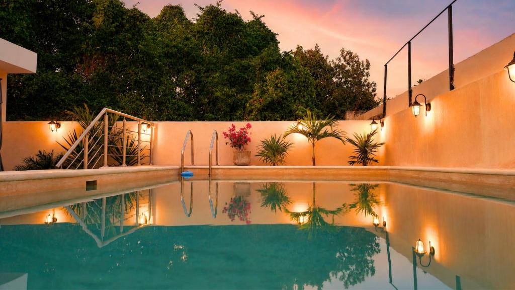 a swimming pool with lights on the side of a house at Hotel Casa Vivaldi in Mérida