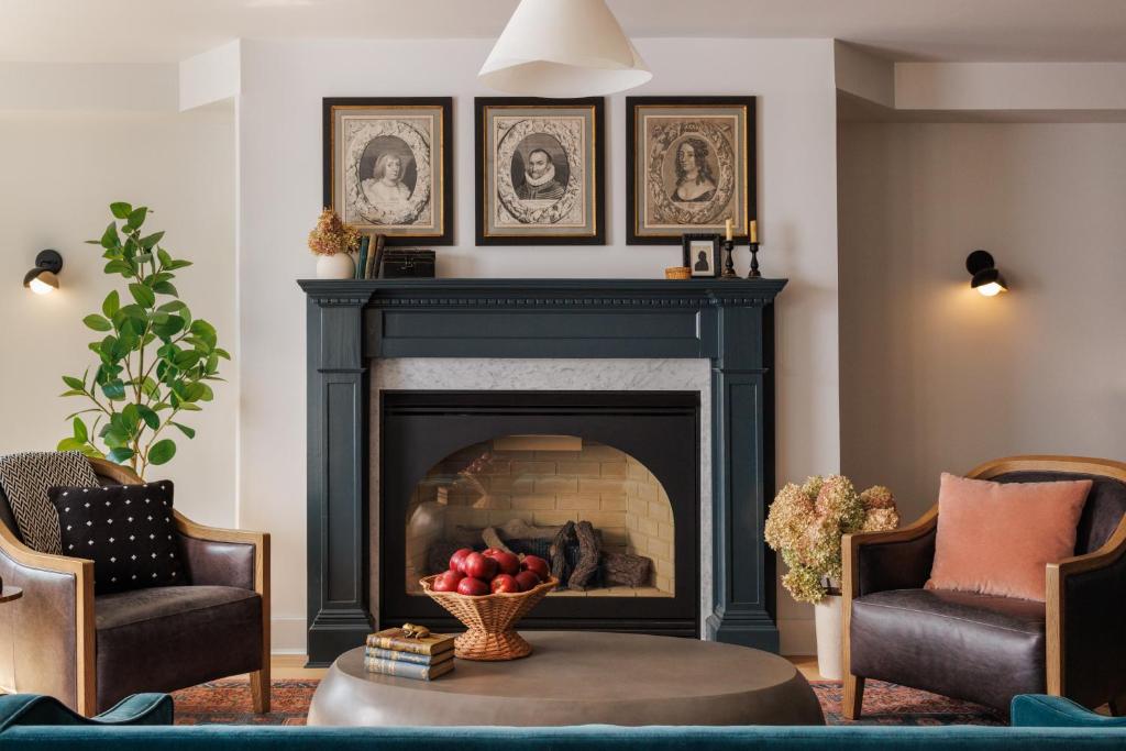a living room with a fireplace and two chairs at Old Dutch Inn in Kinderhook