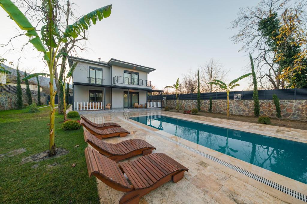 a house with a swimming pool with three chairs next to it at Luku Villa in Sapanca