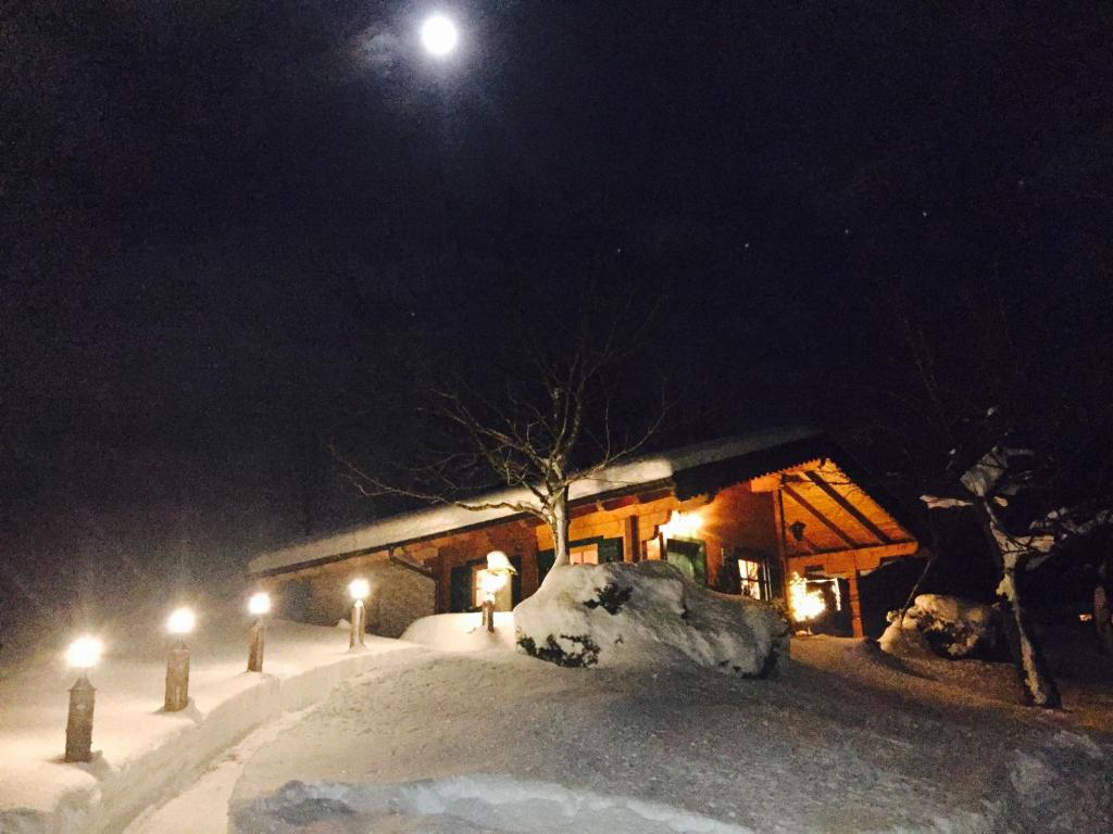 una cabaña en la nieve por la noche con la luna en Jagdhütte en Abtenau