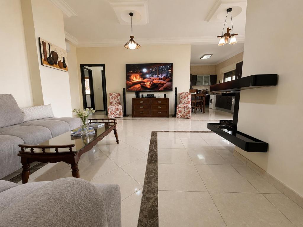 a living room with a couch and a table and a tv at Cozy Central Secured Compound in Amman