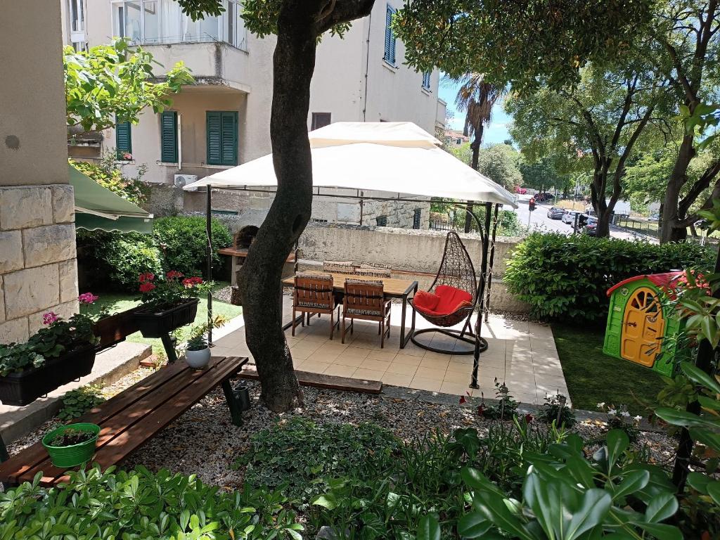a patio with a table and a swing and an umbrella at Garden apartment Vanya in Split
