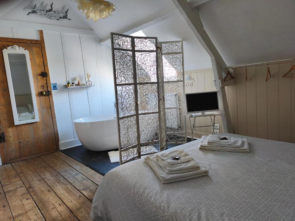 a bathroom with a bed and a tub and a television at Chambres d'hôtes Atypik in Dieppe