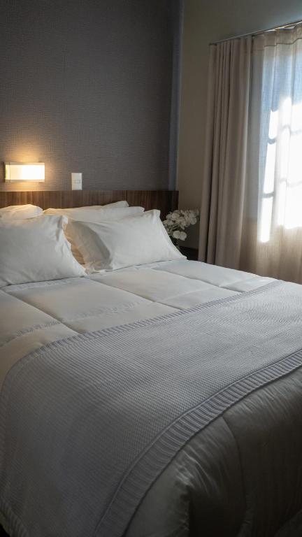 a large white bed in a bedroom with a window at Nohotel Nova Odessa in Nova Odessa