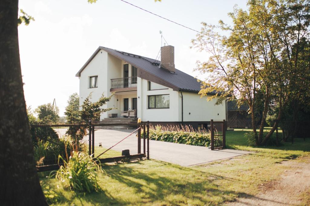 a white house with a black roof at MADARAS Country house in Ventava