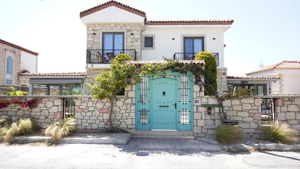a house with a blue door and a stone wall at My Angels Alaçatı in Alaçatı
