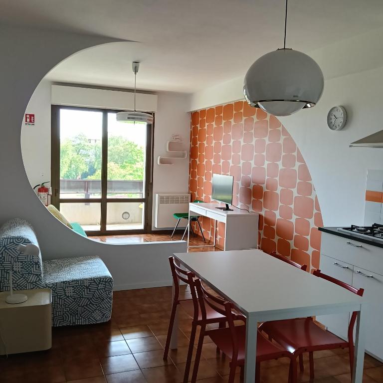 a living room with a table and a desk with a laptop at Appartamento Velocipede in Cervignano del Friuli