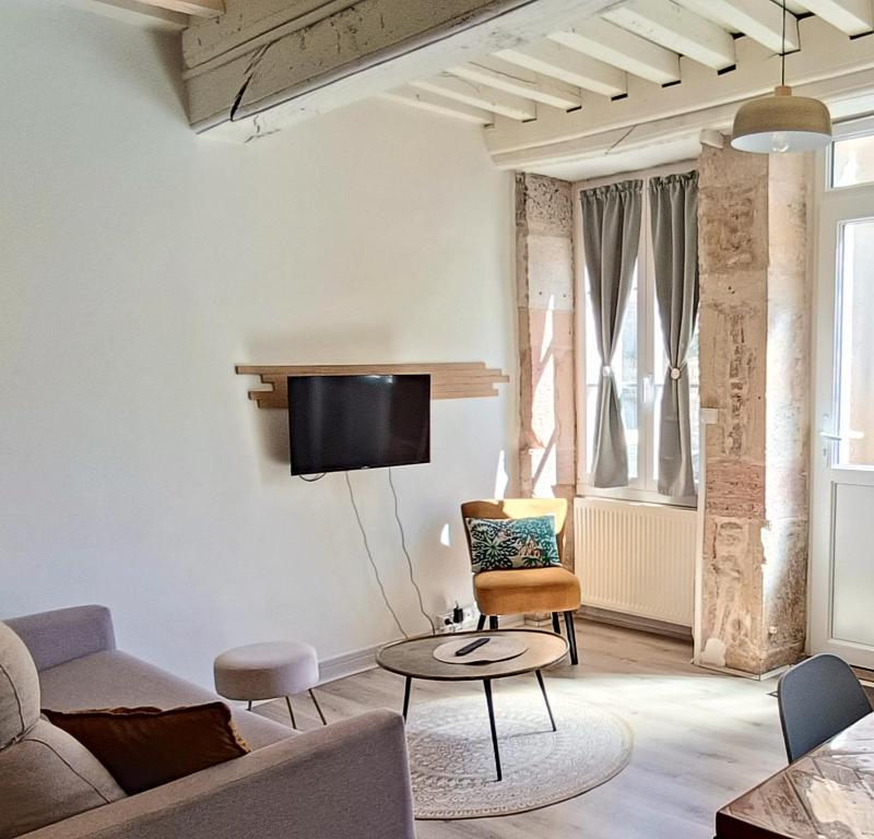 a living room with a couch and a tv on a wall at Le gîte de Varanges in Givry