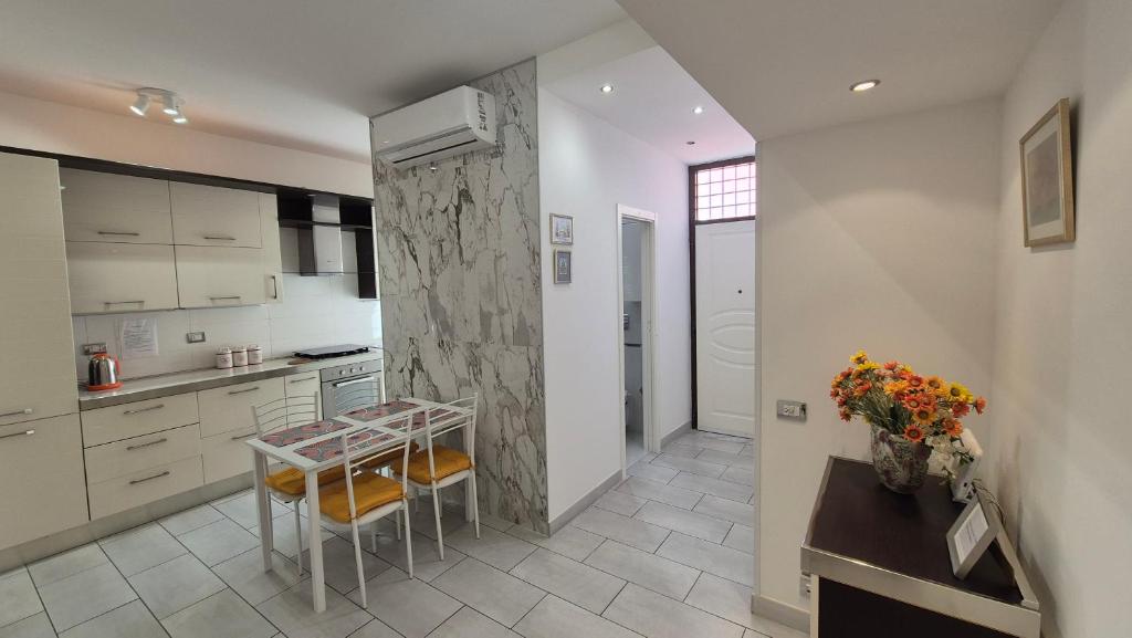 a kitchen with white cabinets and a table and chairs at Ladispoli Apartment in Ladispoli