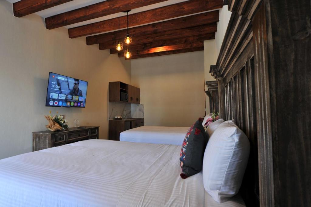 a bedroom with two beds and a flat screen tv at Hotel Camino Del Bosque Centro Pádel in Cholula