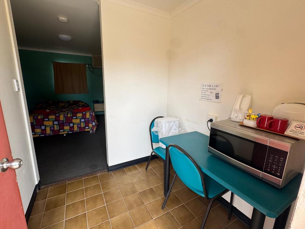 a room with a table with a microwave and a bed at Coyote Inn in Cloncurry