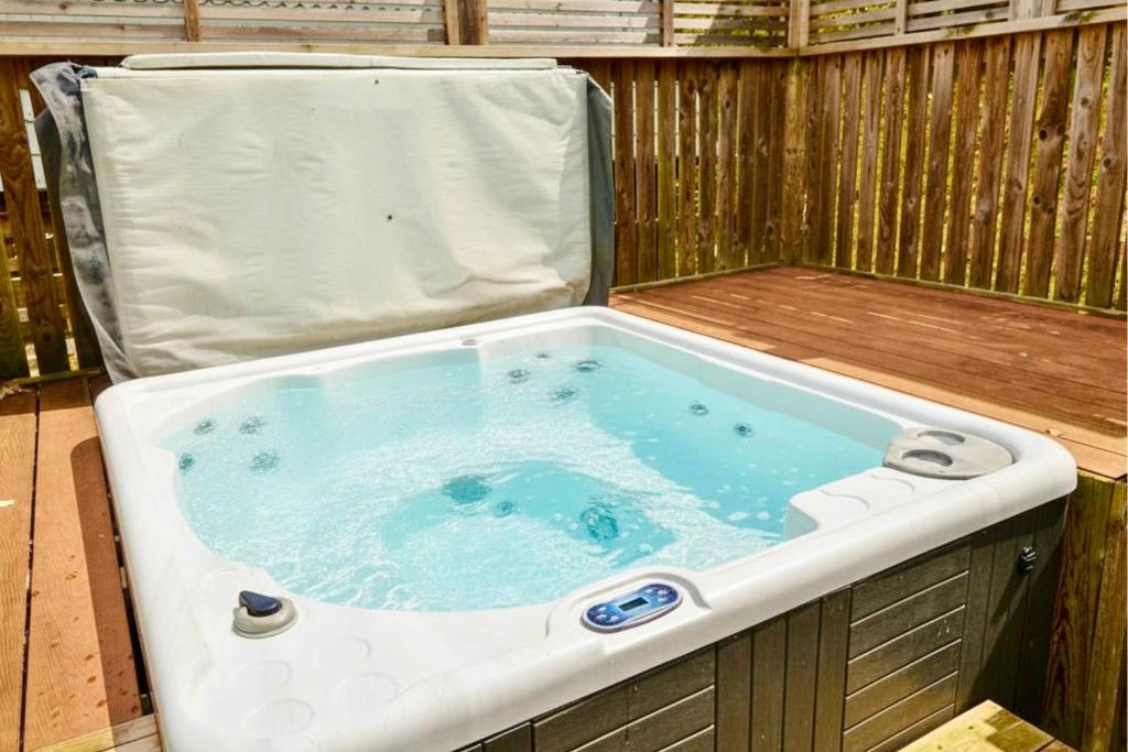 a jacuzzi tub sitting in a wooden deck at Primrose Lodge with Hot Tub near Waterpark and Trails in Chudleigh