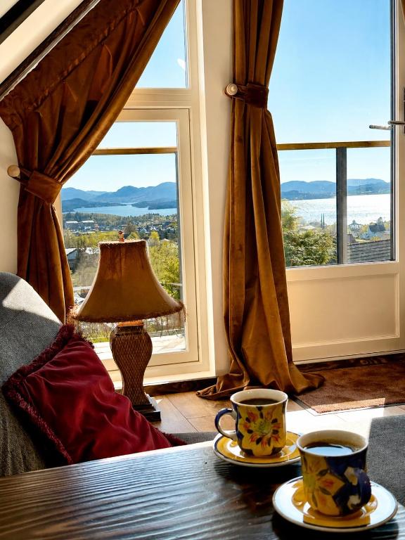 two cups of coffee on a table in front of a window at Fjord Panorama Lodge in Strand