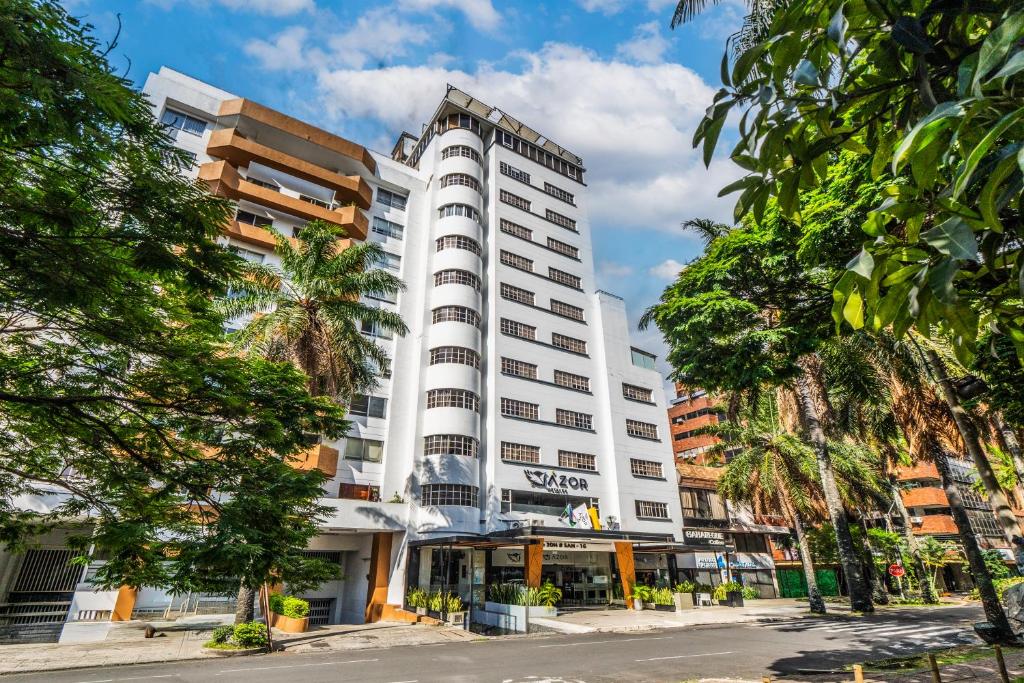a white building with trees in front of it at Azor Hotel Cali Versalles in Cali