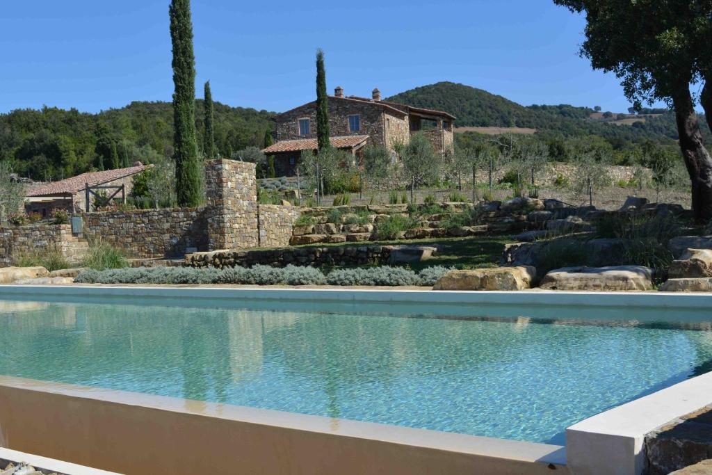 a swimming pool in a garden with a house in the background at Le Moraiole in Massa Marittima