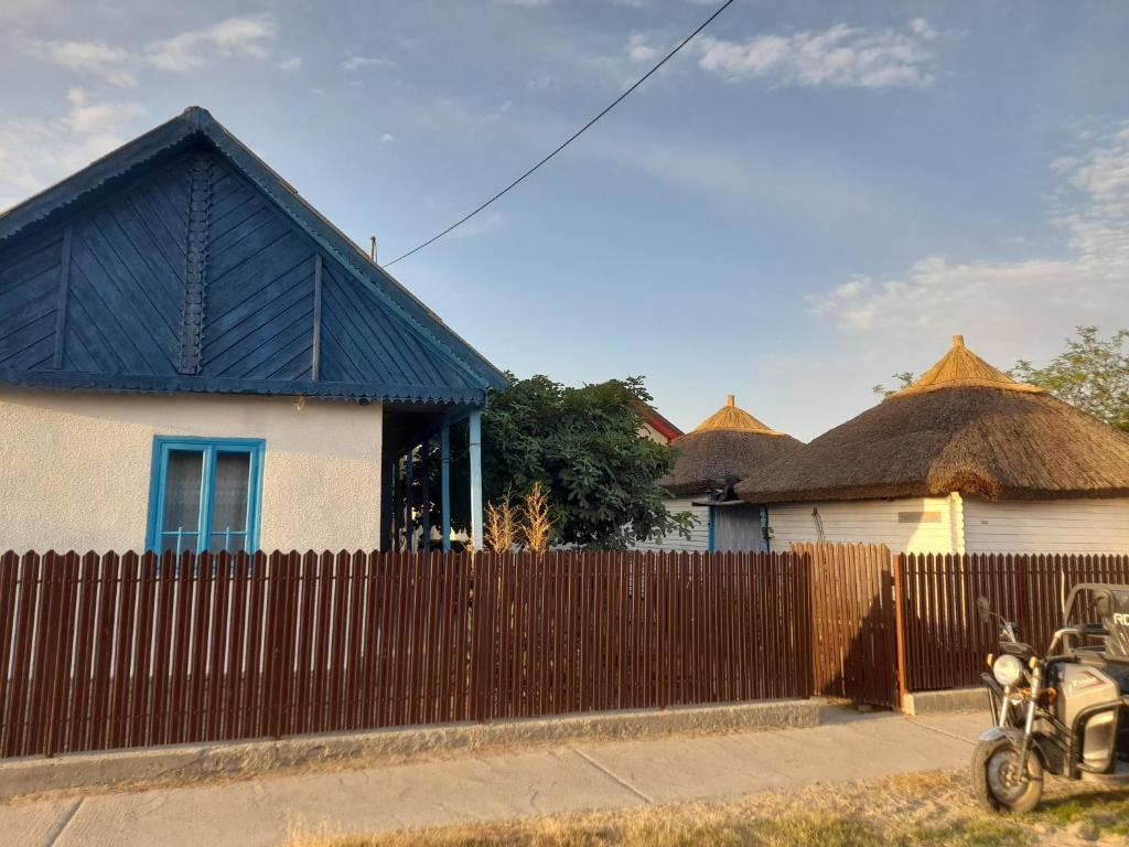 a house with a fence and a motorcycle parked in front at Casa de vacanta Amira in Sfântu Gheorghe