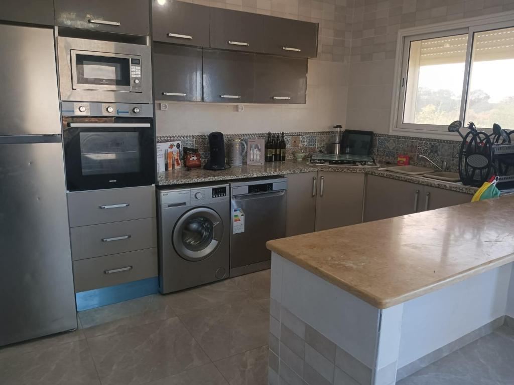 a kitchen with a dishwasher and a washer and dryer at Maison ras angela in Bizerte