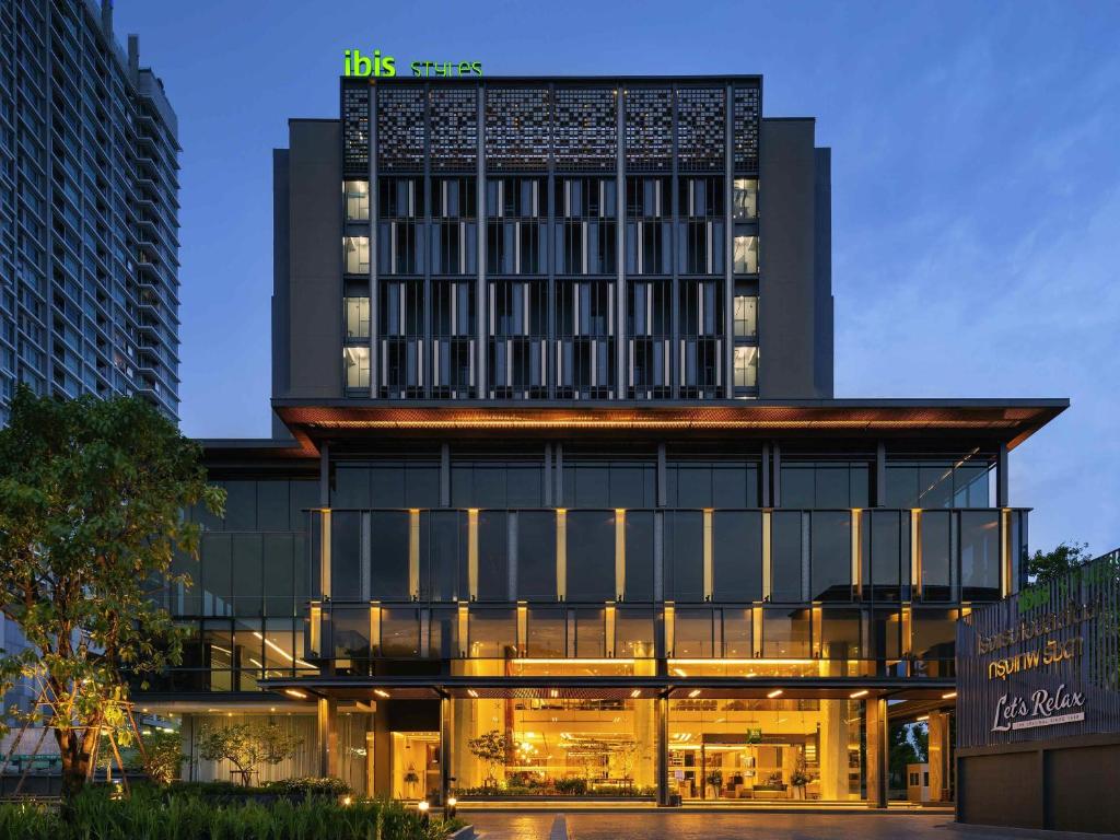 a hotel building with a lit up facade at night at ibis Styles Bangkok Ratchada in Bangkok