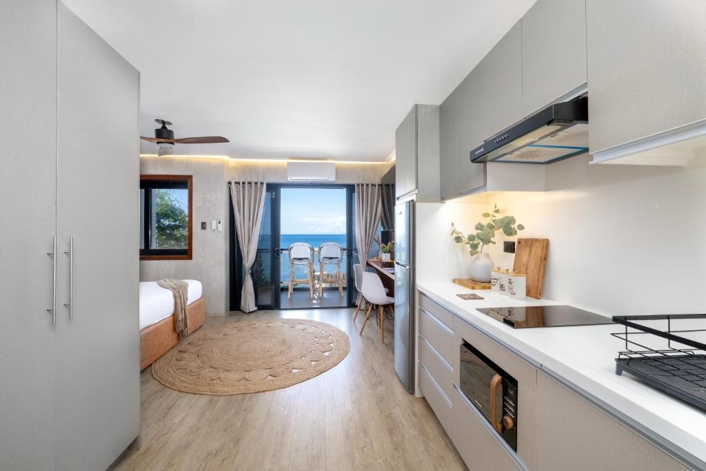 a room with a kitchen and a bedroom with a bed at Bonbon Beach House in Liloan