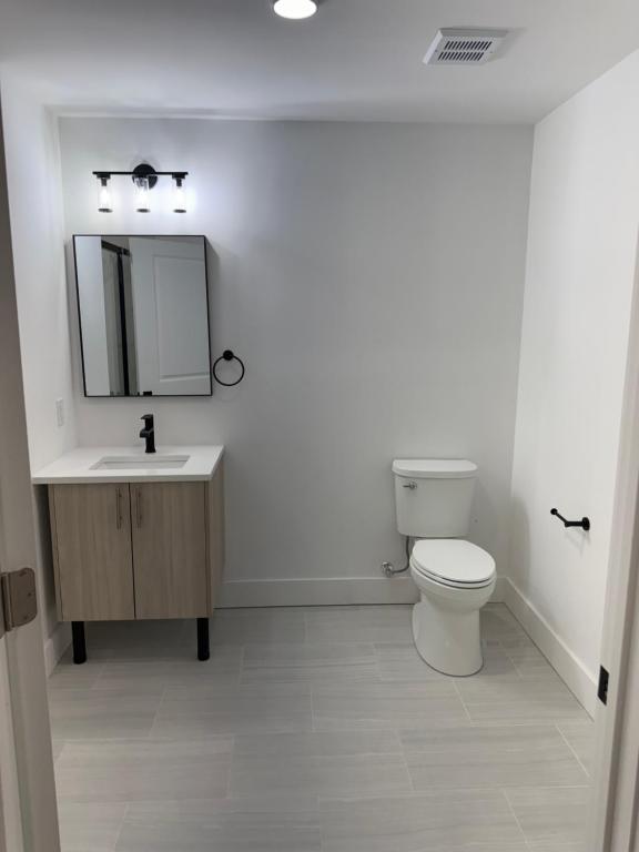 a bathroom with a toilet and a sink and a mirror at 2 Bedroom Apartment in Seaside Heights