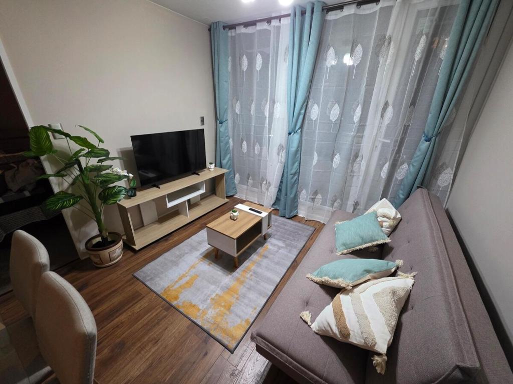 a living room with a couch and a tv at Dpto 2D2B Barlovento Brisas del Sol in Talcahuano