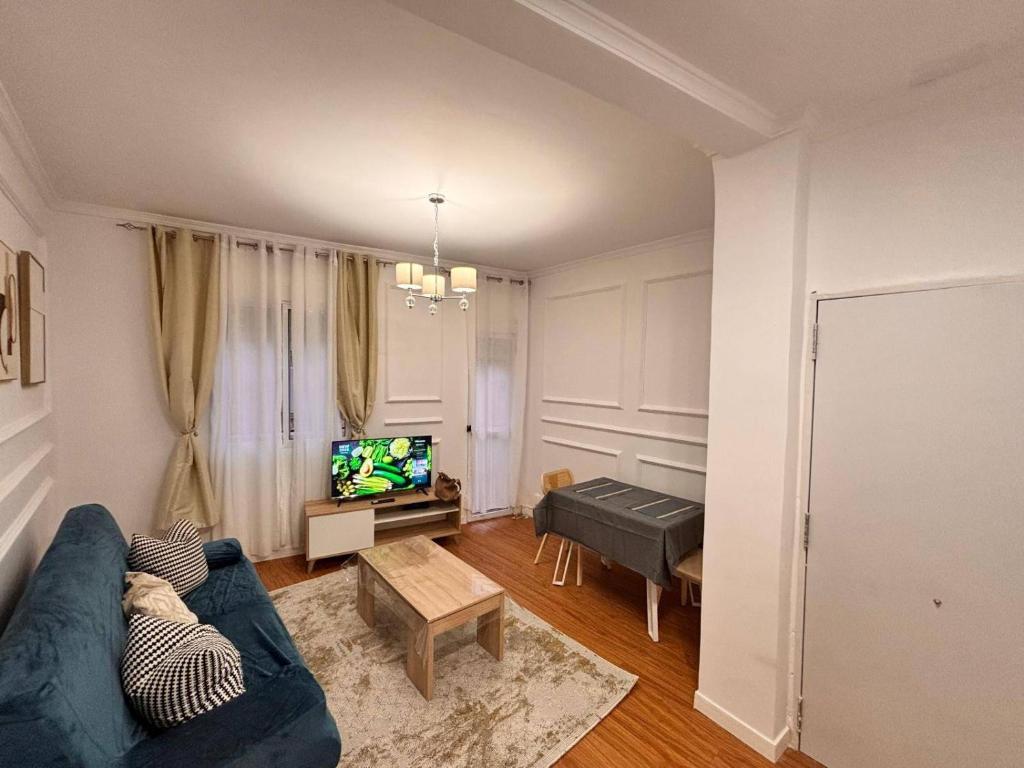 a living room with a blue couch and a tv at Pretty central flat in Ceuta