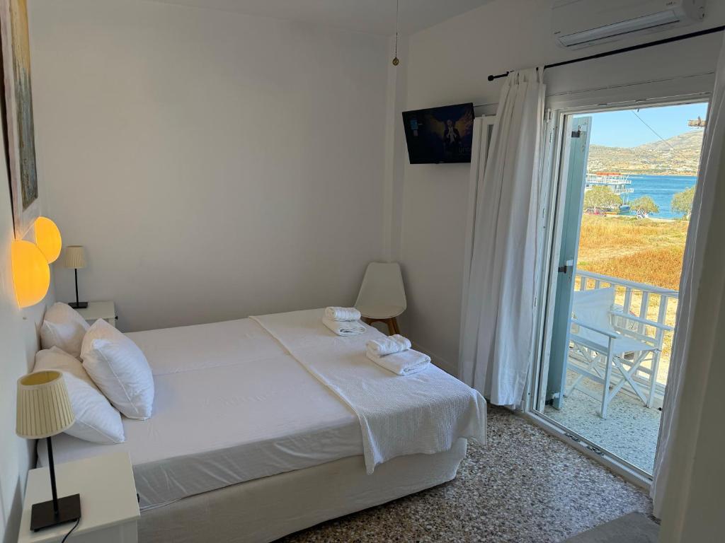 a white bedroom with a bed and a balcony at Windmill Rooms in Antiparos