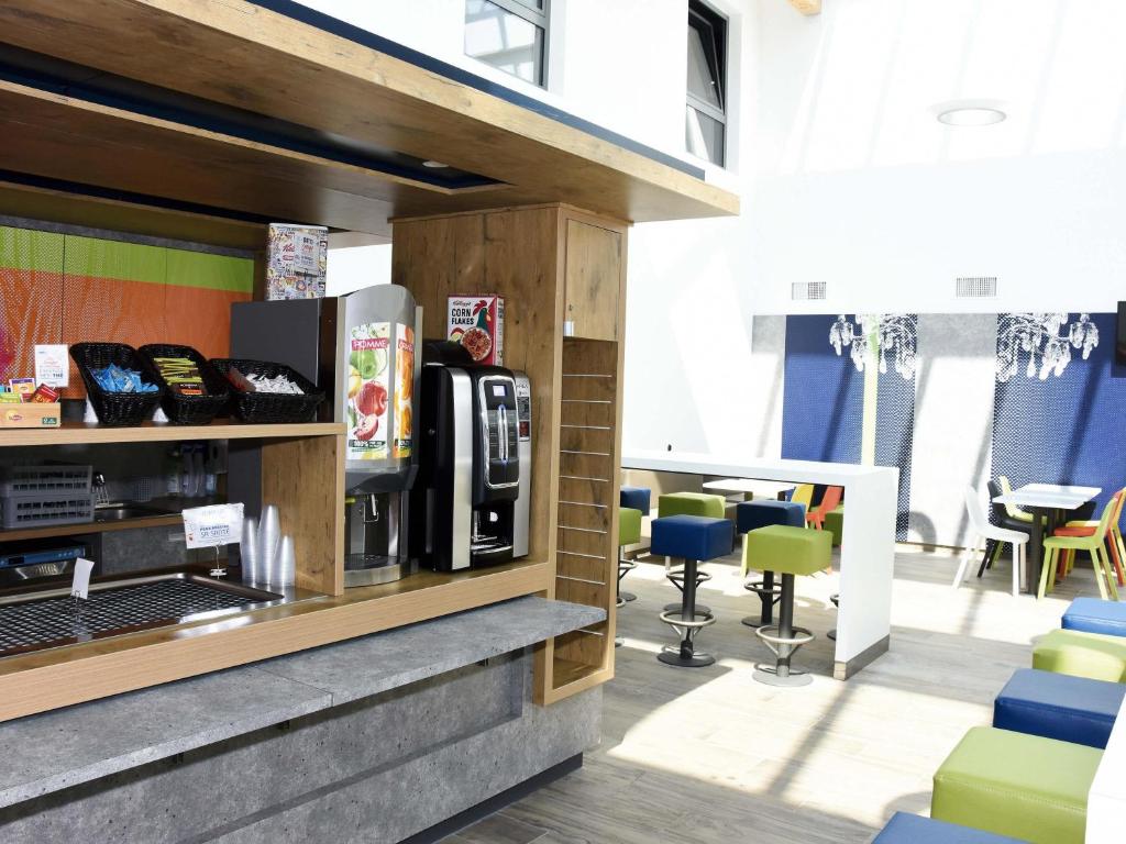 a coffee shop with a counter and chairs at ibis budget Langres in Langres