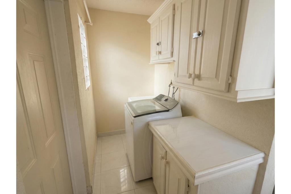 a small white bathroom with a washer and dryer at Pink Sands-At Bel Air in Saint Philip