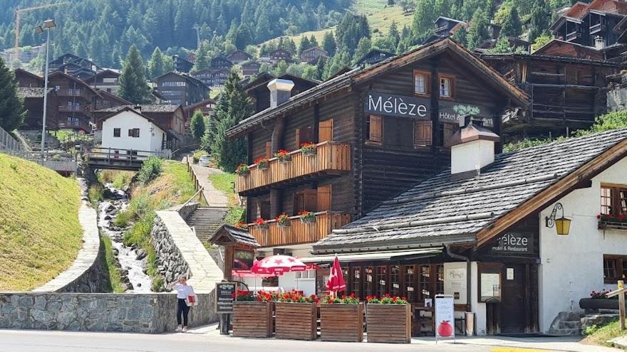 a man standing in front of a large building at Hôtel-Restaurant Mélèze Grimentz in Grimentz