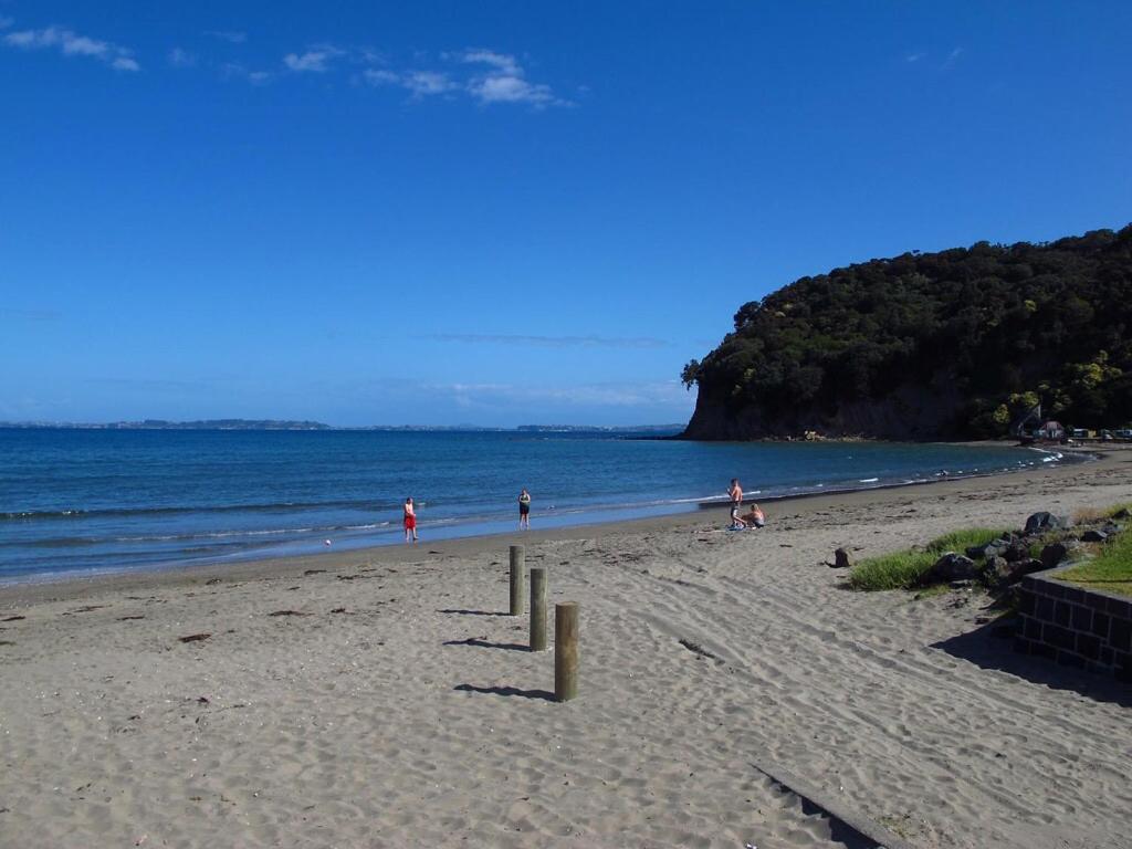 a group of people on a beach near the water at Waiwera Beach GetAway in Waiwera