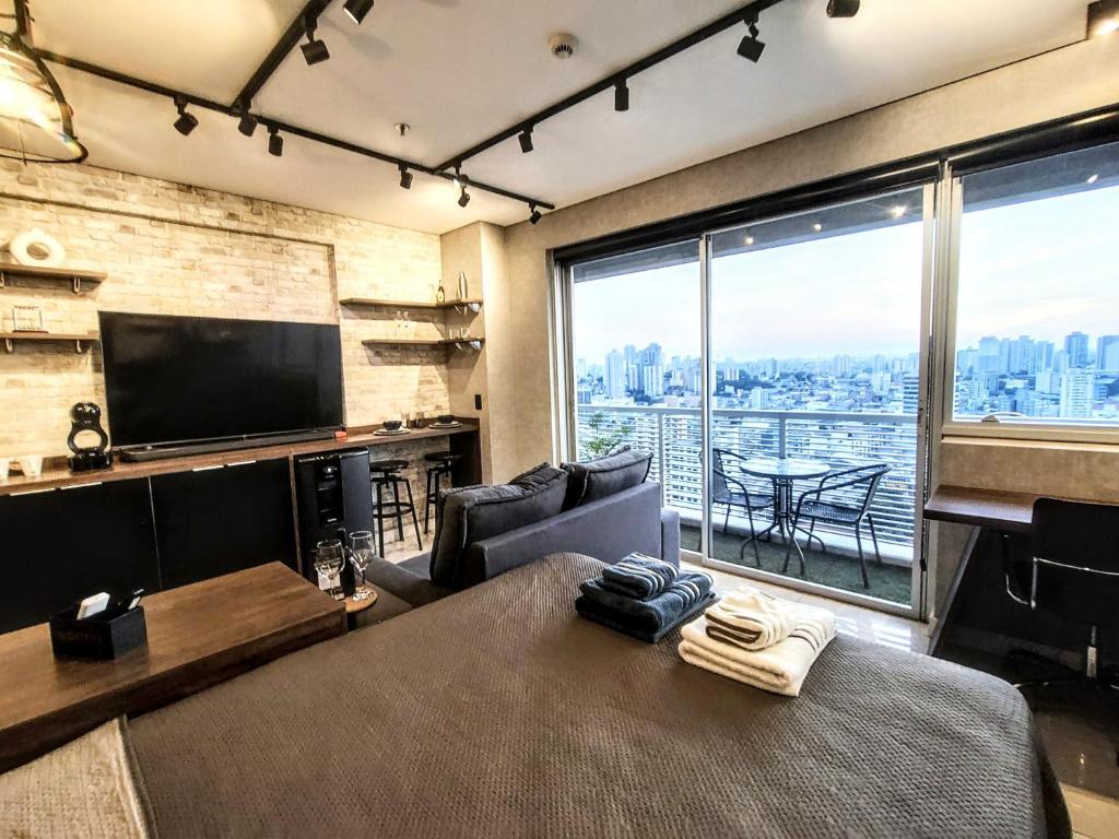 a living room with a large window and a television at The Cittyplex Home Osasco Estilo & Conforto in Osasco