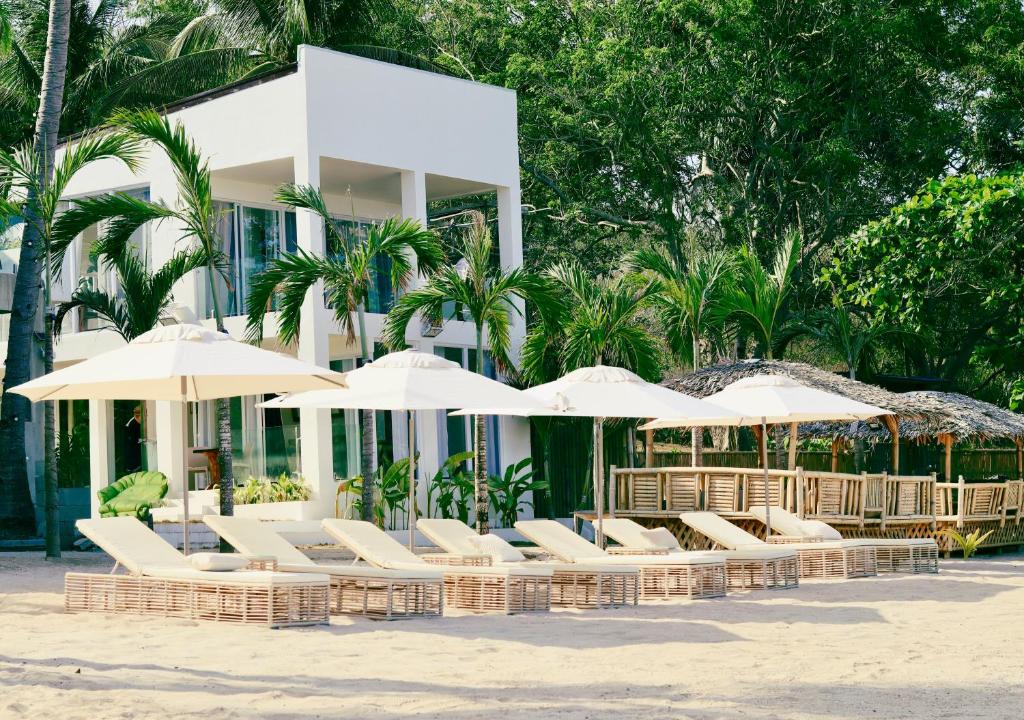 a group of chairs and umbrellas in front of a building at Binucot Pearl Boutique Resort in Ferrol
